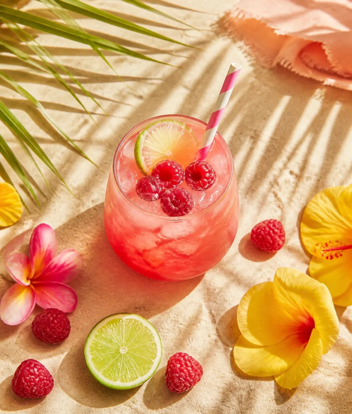 Cocktail framboise sur sable avec fleurs tropicales