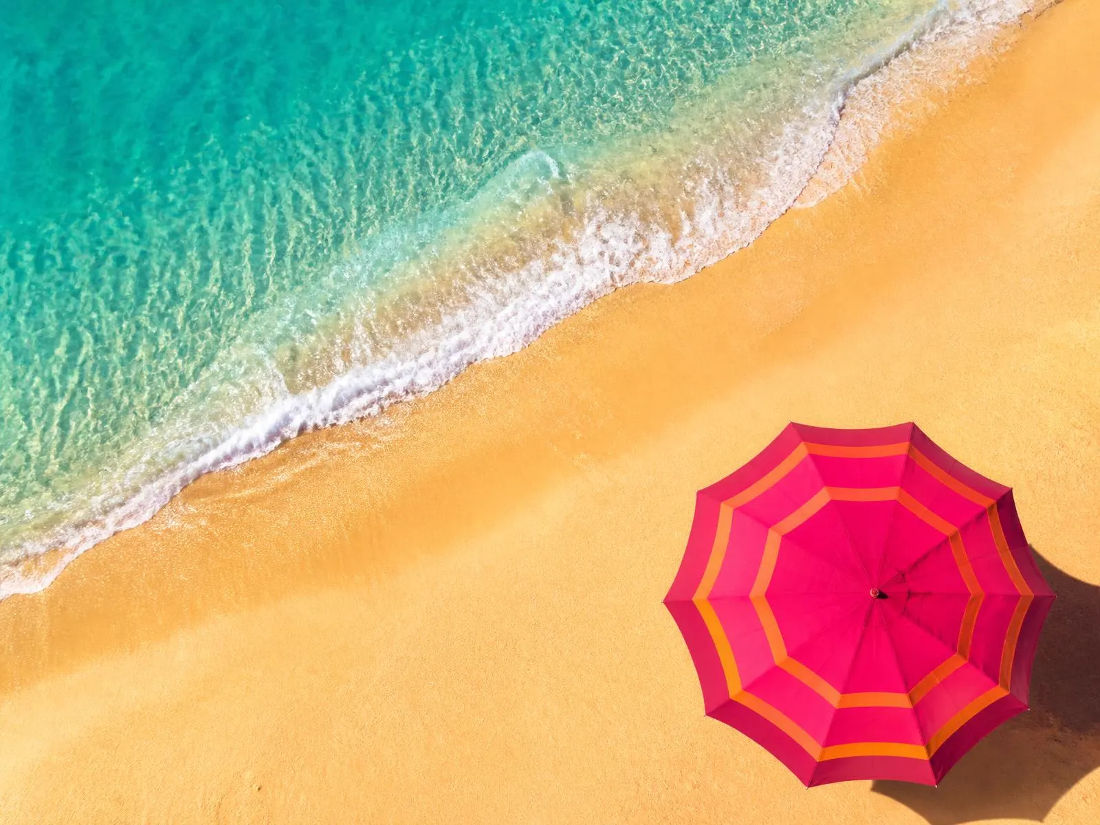 Plage tropicale avec parasol framboise vue du ciel